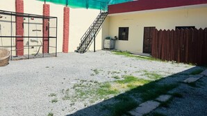 Ein Gebäude mit einem Kieshof, einem Metallgitter, einem Holzzaun und einer Treppe, die zu einer Tür führt.