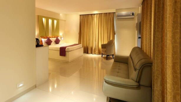 Ein Hotelzimmer mit Bett, Sofa, Sessel, Fernseher und Klimaanlage.