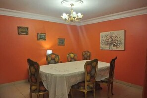 Ein Esszimmer mit einem runden Tisch, Stühlen, einer Chandelüstere und gerahmten Bildern an den Wänden.