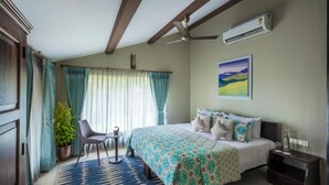 A bedroom with a bed, a small table, a chair, a potted plant, and a painting on the wall. - Ama Stays & Trails Sluice House, Lonavala (Mawal)