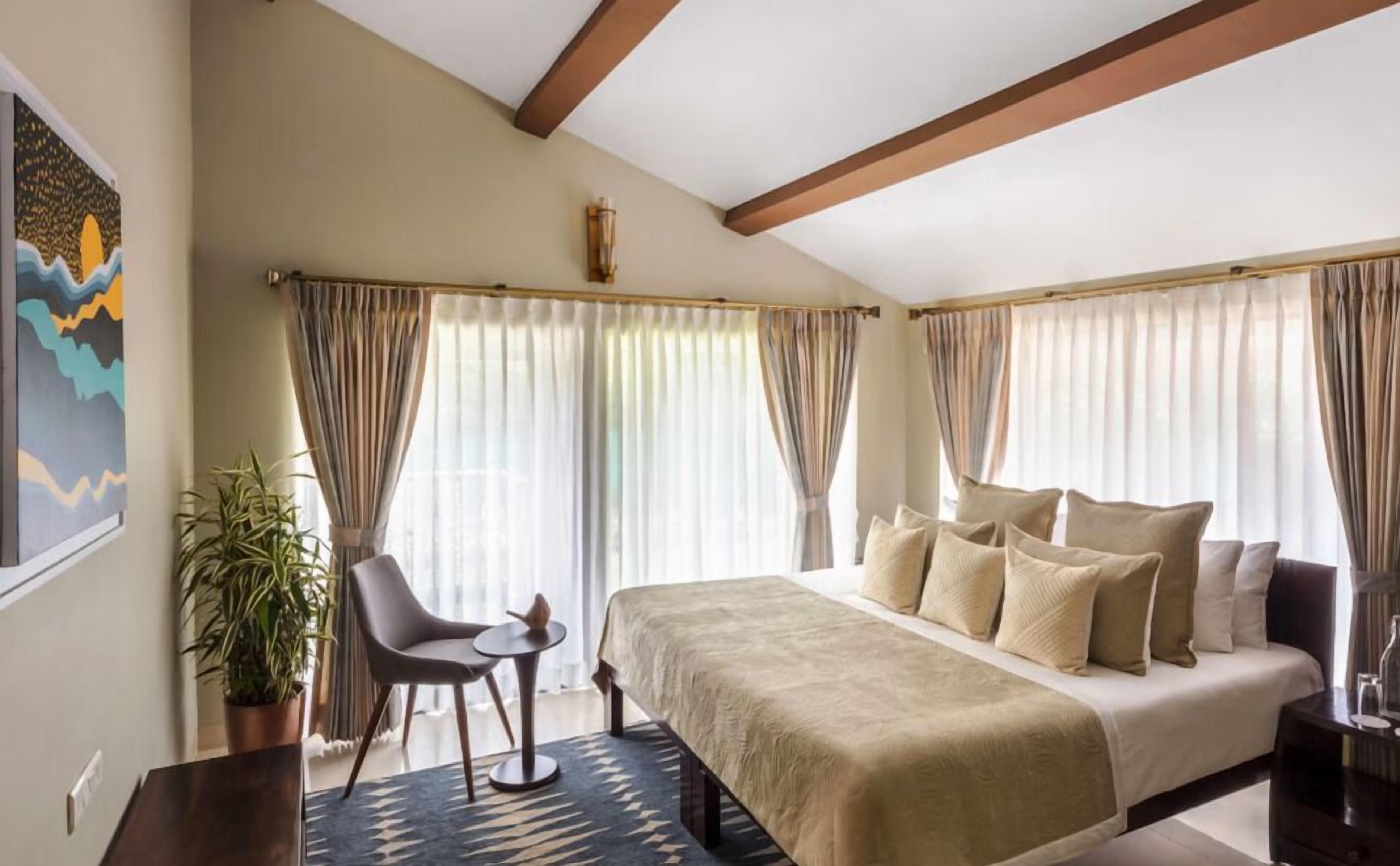 Ein Schlafzimmer mit einem Bett, einem Sessel, einem kleinen Tisch und einer Topfpflanze.