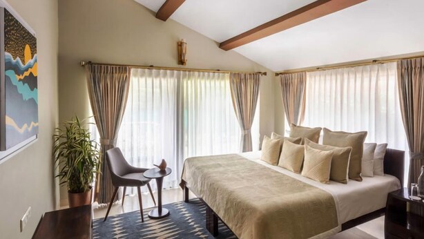 A bedroom with a bed, a chair, a small table, and a potted plant. - Ama Stays & Trails Sluice House, Lonavala (Mawal)