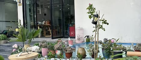 A patio with potted plants, a large barrel, and various bottles.