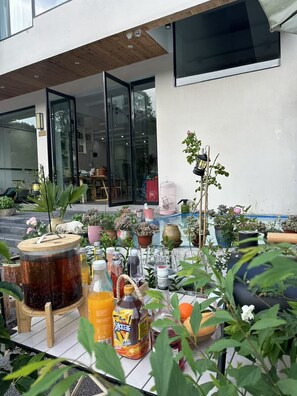 Une terrasse agrémentée de plantes en pot, d’un grand tonneau et de diverses bouteilles.