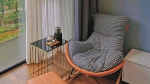 A modern room with a view of greenery, a houndstooth patterned chair, a small table with cups, and a decorative wall piece. - Zhangjiajie Southgate Flower Garden Lodge at the Park Entrance (Zhangjiajie)