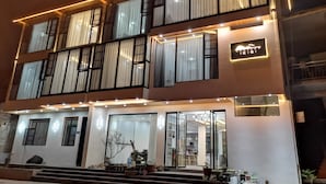 A multi-story hotel with a modern design, featuring large windows with curtains, a well-lit entrance, and a visible signboard. - Zhangjiajie Southgate Flower Garden Lodge at the Park Entrance (Zhangjiajie)