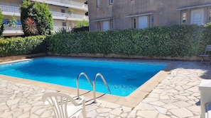 A rectangular swimming pool with metal ladders, surrounded by stone tiles and a hedge. - Exceptional garden level pool cap d'antibes (Antibes)
