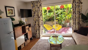 A living room with a sofa, a TV, a table, and a window with curtains. - Exceptional garden level pool cap d'antibes (Antibes)