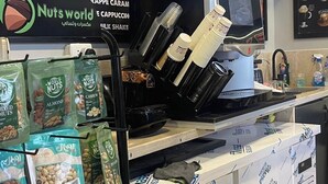 En cafédisk med kaffemaskine, kværn og udstilling af pakker med nødder.