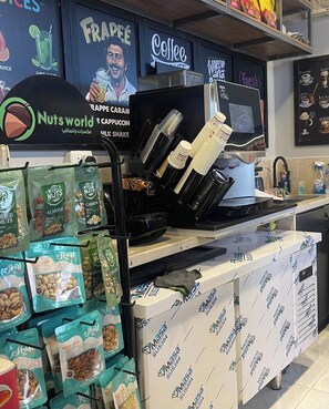 Ein Tresen in einem Café mit einer Kaffeemaschine, einer Kaffeemühle und einer Auswahl an verpackten Nüssen.