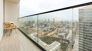 Ein Hotelzimmer in einem Hochhaus mit Panoramablick auf die Stadt, einer Glastrennwand und einer Sitzecke mit Stühlen.