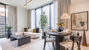 Ein modernes Wohnzimmer mit Sofa, Couchtisch, Esstisch, Stühlen und einer Topfpflanze.