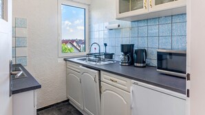 A modern kitchen with white cabinets, a black countertop, a coffee maker, and a microwave.