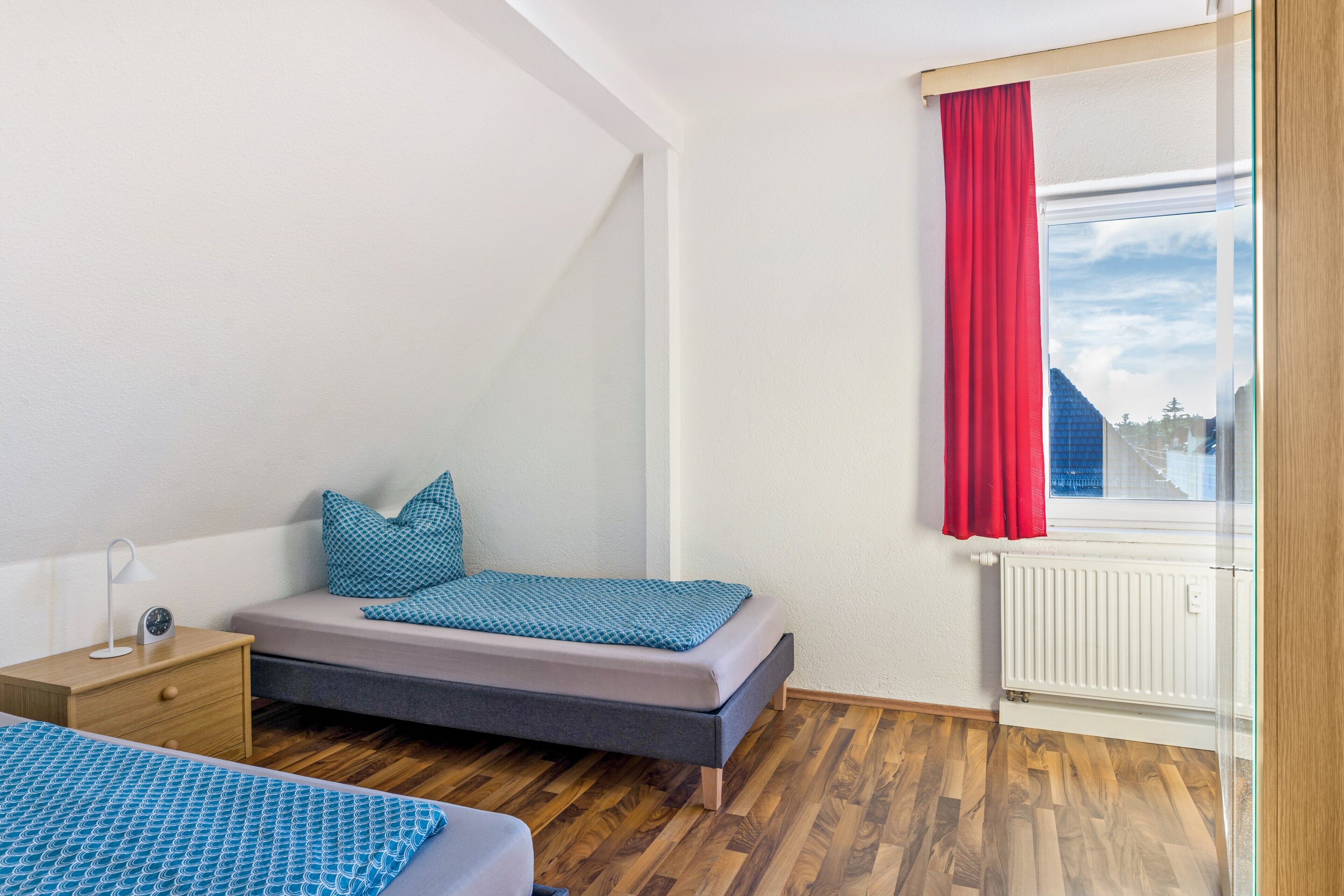 A bedroom with a bed, bedside table, and a window with curtains.
