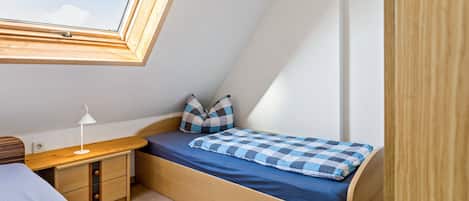 Un dormitorio compacto con cama elevada, un escritorio y ventana con vista al cielo.