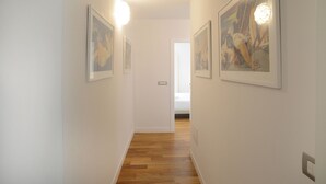 A hallway with wooden flooring, white walls, and framed artwork on the walls. - Lecasinedigiò1 Spacious penthouse with large terrace overlooking the sea (Alghero)