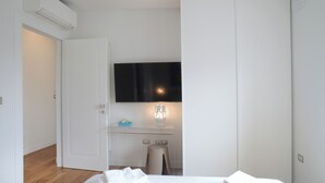 A bedroom with a bed, a desk, a chair, a TV, and a wardrobe. - Lecasinedigiò1 Spacious penthouse with large terrace overlooking the sea (Alghero)