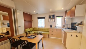 Een kleine leefruimte met een eethoek, kitchenette en een groene bank.