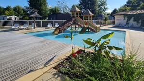Zwembad met glijbaan, ligbedden en een houten terras.
