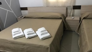 Habitación de hotel con dos camas, cada una con una colcha y almohadas color beige, y una mesita de noche con un teléfono.