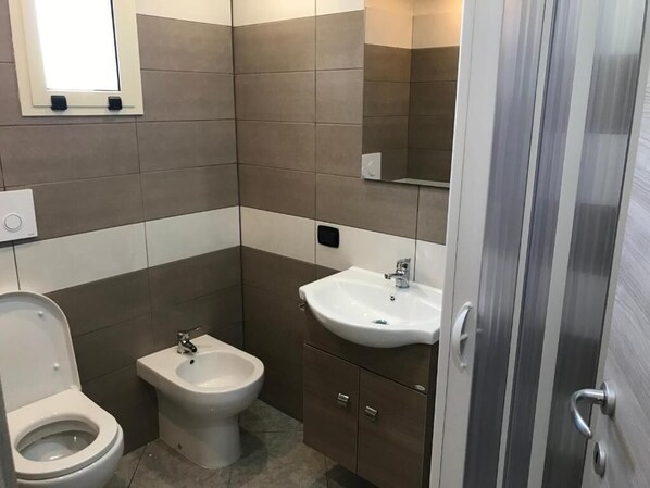 Un baño con inodoro, bidé y lavamanos.