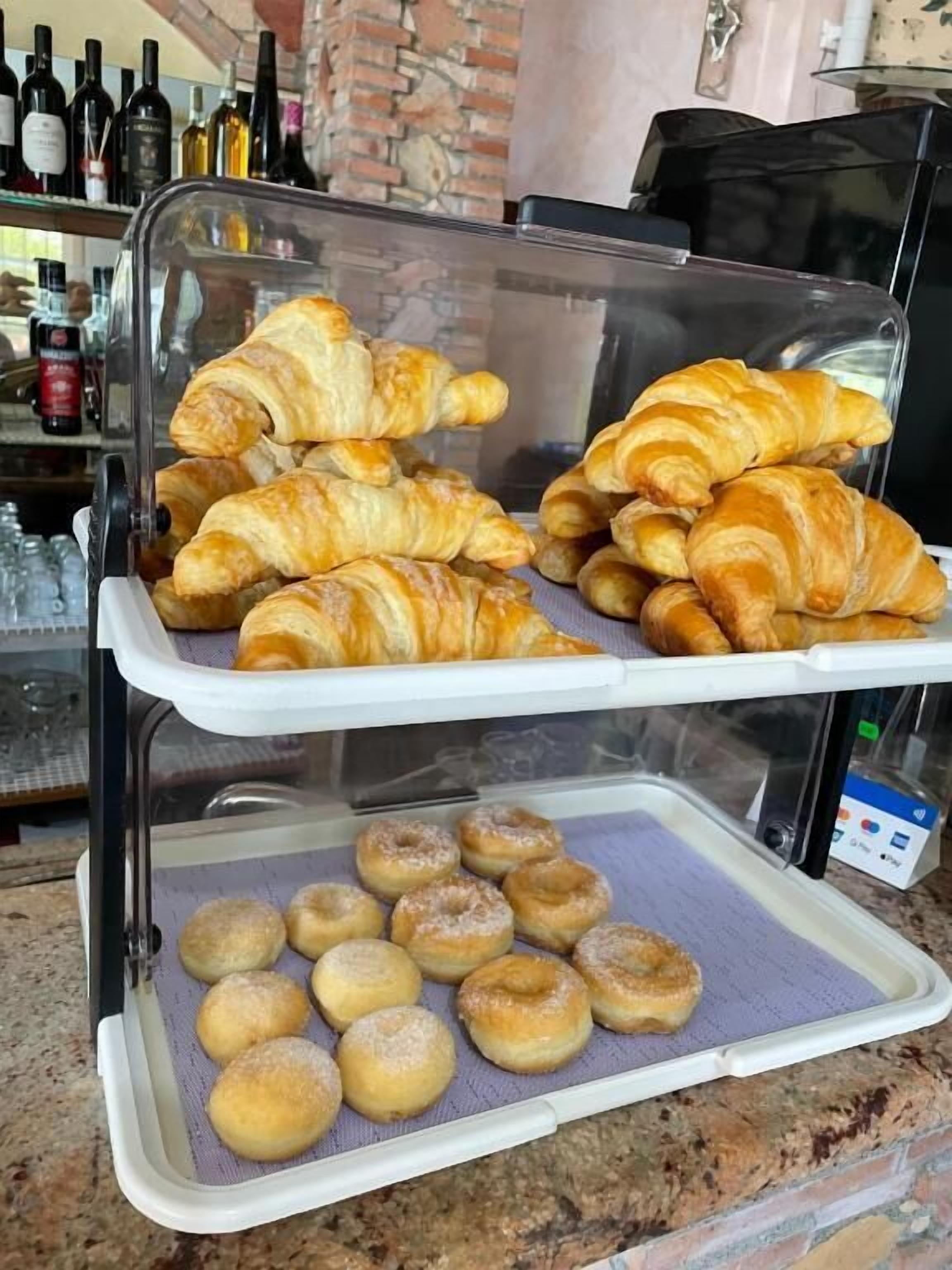 A bakery display case with croissants and doughnuts.