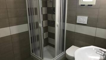 A bathroom with a shower, toilet, and sink.