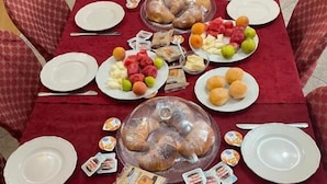 Mesa de comedor servida con platos, cubiertos y diferentes alimentos.