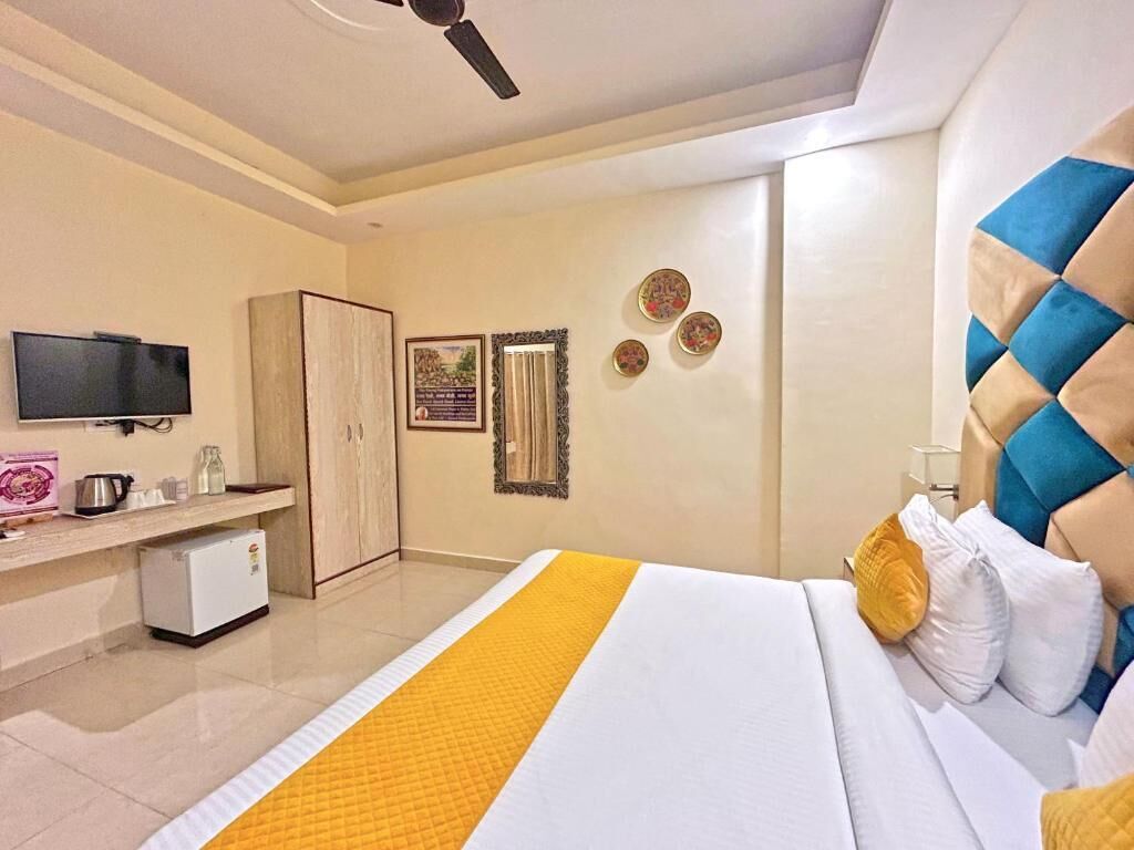 A hotel room with a bed, a television, a wardrobe, and a small refrigerator.