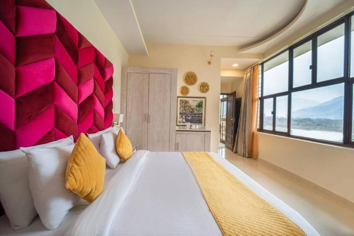 Habitación de hotel con una cama grande, vistas a la montaña, un armario de madera y una pared con diseños geométricos.