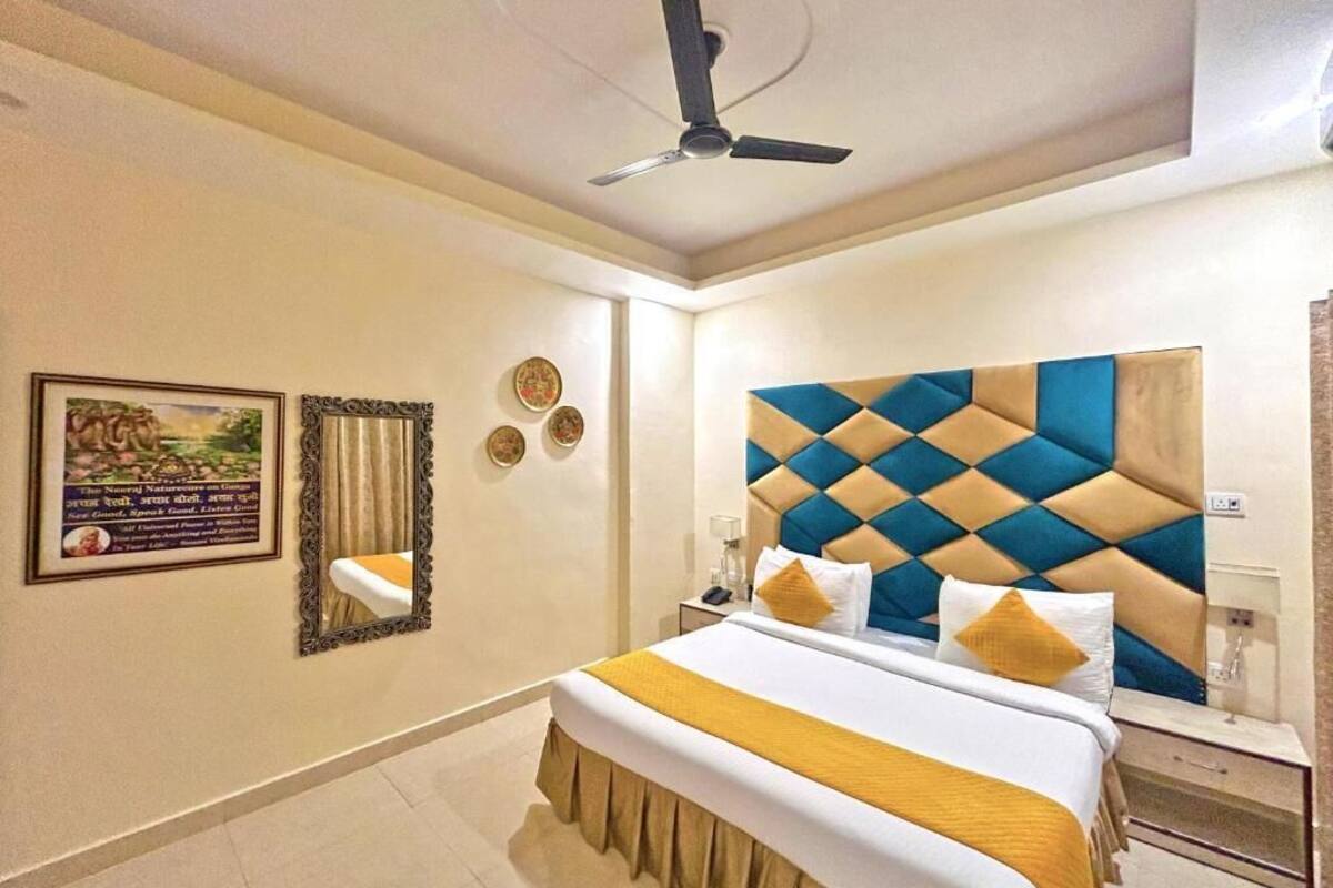 Una habitación de hotel con una cama, un ventilador de techo, una mesita de noche y una pared con cuadros enmarcados.