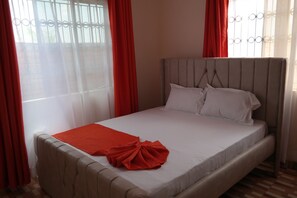 A bed with a white mattress, a red blanket, and a matching red pillow. - Fabulous 1-bedroom bungalow in enjoyable Voi, Taita-Taveta County (Taita-Taveta County)