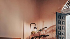 En hyggelig stue med en sofa, en gulvlampe, en potteplante og et mønstret tæppe.