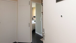Un pasillo con una puerta cerrada, un timbre y un letrero en la pared que indica la habitación número 12.