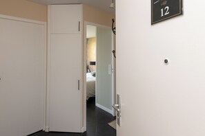 Ein Flur mit geschlossener Tür, Klingel und einer Wandtafel mit der Zimmernummer 12.