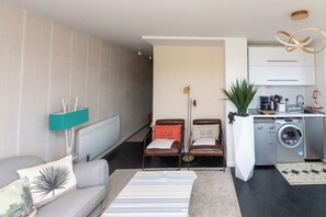Ein modernes Wohnzimmer mit Sofa, Couchtisch, Waschmaschine und Essbereich mit Stühlen.