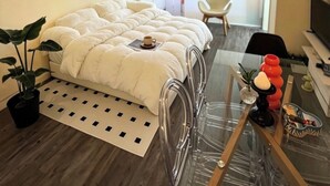 Una camera da letto moderna con un letto grande, un lampadario, un tavolino in vetro e una pianta in vaso.