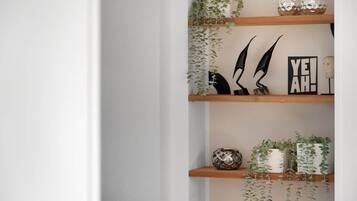 Uno scaffale con oggetti decorativi, tra cui una pianta, una scultura astratta in bianco e nero e un cartello con la scritta 'YE!AH!'.