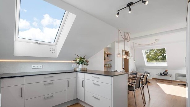 Een moderne keuken met een dakraam, een eethoek met stoelen en uitzicht op de omgeving.
