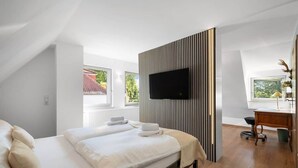 Een moderne slaapkamer met een bed, een televisie aan de muur en een bureau met stoel.