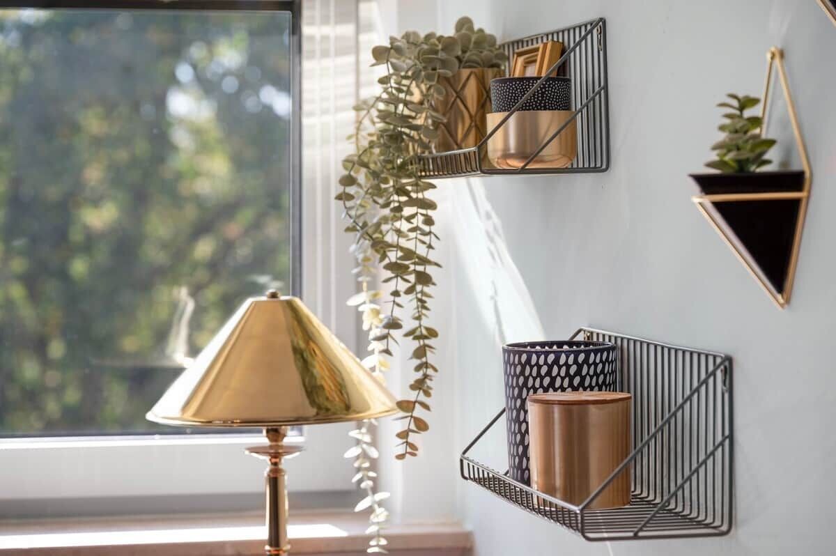 A room with a window, a lamp, and wall-mounted shelves with decorative items.