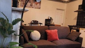 Ein Wohnzimmer mit einem braunen Sofa, einem weißen Couchtisch und einer Topfpflanze.
