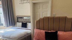 Ein Schlafzimmer mit zwei Betten, einem Kopfteil, einer Wand mit einem Zitat und einer Tür.