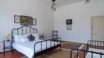 A bedroom with a metal bed frame, a bedside table with a lamp, a rug, and artwork on the wall.
