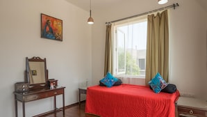 A bedroom with a bed, a nightstand, a dresser, a mirror, and a window with curtains. - Ama Stays And Trails Casa Kenzo Kashid (Murud)