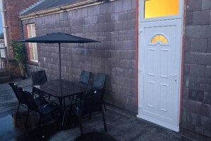 A patio with a table and chairs, a door with a window, and a brick wall. - Glams 2beds luxury stylish apartment (Wolverhampton)