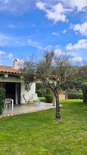 Ein Haus mit Terrasse, einem Baum und wolkenlosem, blauem Himmel.