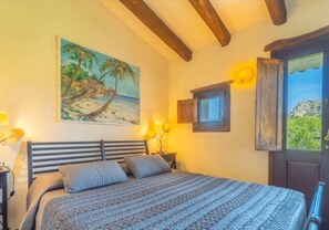 Ein Schlafzimmer mit einem Bett, einem Strandbild, einem Fenster mit Aussicht und einer Holzzieldecke.