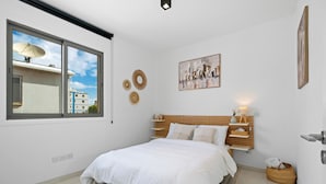Une chambre à coucher avec un lit, une fenêtre, un tableau et une étagère fixée au mur.
