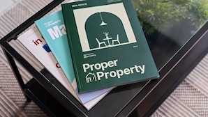 Un livre intitulé « Propriété en règle » est posé sur une table en verre, avec une plante en arrière-plan.